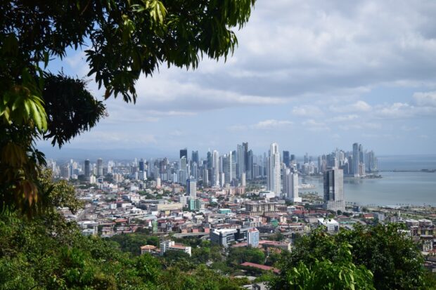 A panoramic view of Panama City skyline with urban buildings and lush greenery in the foreground