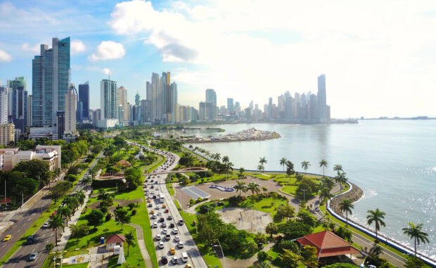 Aerial view of Panama City skyline with green parks and busy roads alongside the waterfront