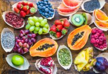 Fresh papaya surrounded by various colorful fruits on wooden table