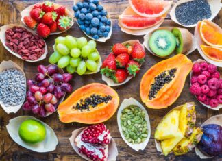 Fresh papaya surrounded by various colorful fruits on wooden table