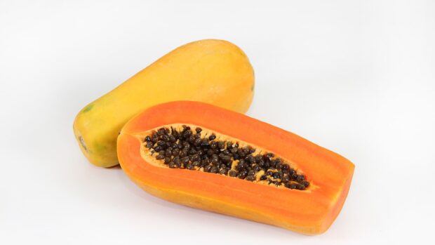 Fresh papaya showing vibrant orange flesh and black seeds on white background