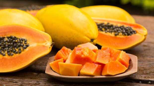 Fresh ripe papaya fruit with juicy pieces on a wooden plate