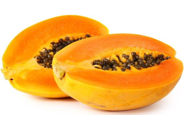 Fresh papaya cut in half showing ripe orange flesh and black seeds on white background