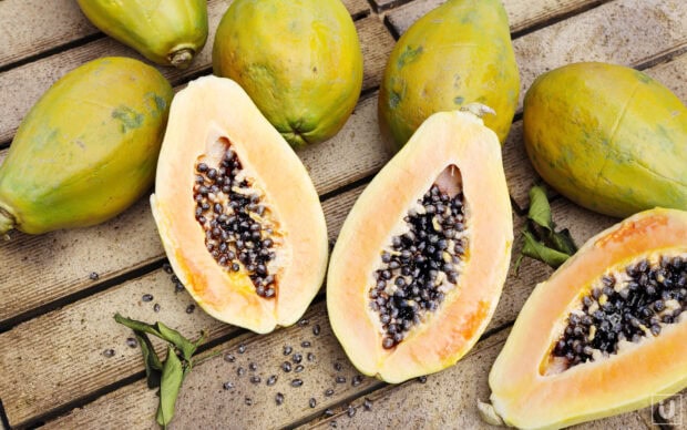 Fresh papaya fruits with seeds placed on wooden surface
