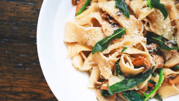 Fresh pasta with mushrooms and spinach served on a white plate
