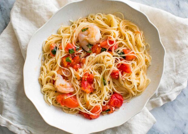 A delicious pasta dish with shrimp and tomatoes served on a white plate