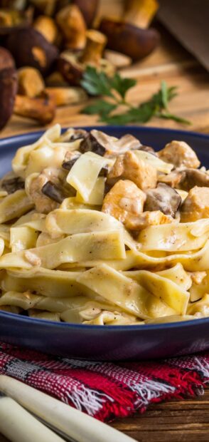 Creamy mushroom pasta with chicken pieces on a plate garnished with parsley