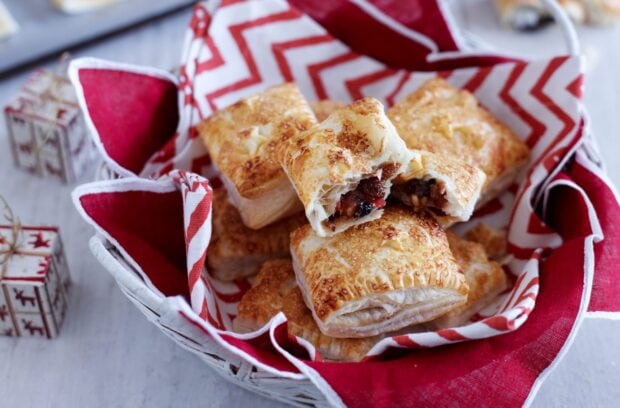 A basket of flaky pastries filled with mixed fruit filling on a red and white cloth