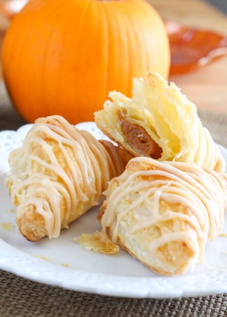 Flaky pastry with creamy filling and frosting on a plate with a pumpkin in the background