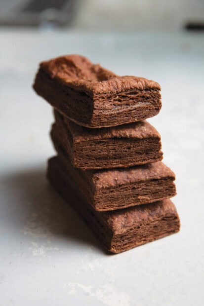 A close up of chocolate pastry layers stacked on a white surface