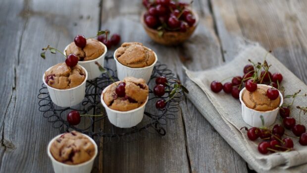 Cherry pastries placed on a rustic wooden table with fresh cherries around them