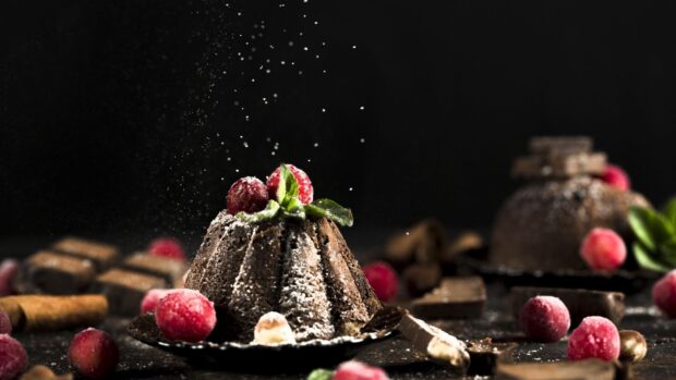 Chocolate pastry dusted with powdered sugar and decorated with red berries and mint leaves