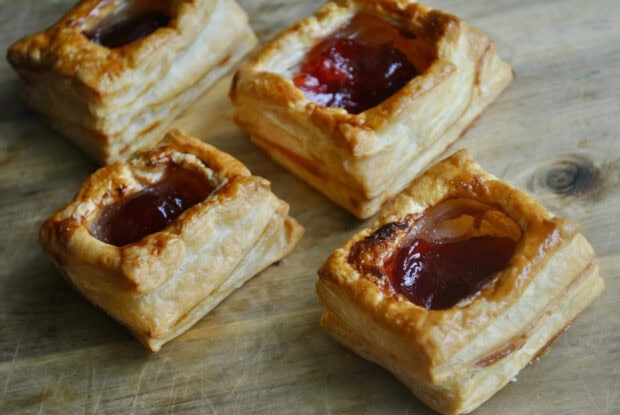Delicious pastry filled with red jam placed on wooden surface