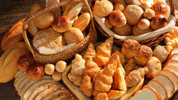 Freshly baked assortment of pastry including croissants and bread loaves in wicker baskets