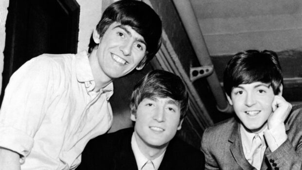 Paul Mccartney with bandmates smiling in a black and white candid portrait
