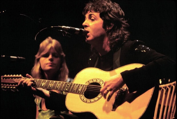 Paul Mccartney playing guitar and singing on stage during a live performance
