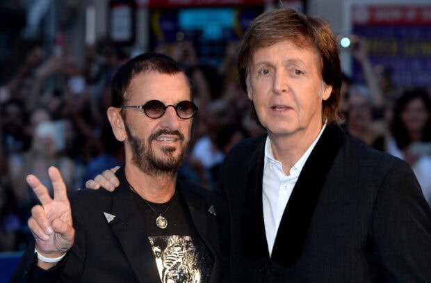 Paul Mccartney standing next to a man wearing round sunglasses at an event