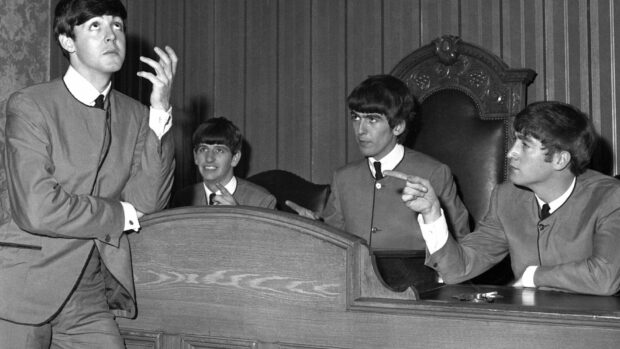 Paul Mccartney and band members in a courtroom scene with Paul Mccartney standing and others pointing fingers