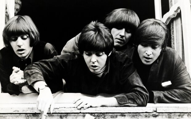 Paul Mccartney and band members looking down with intense expressions in a black and white setting