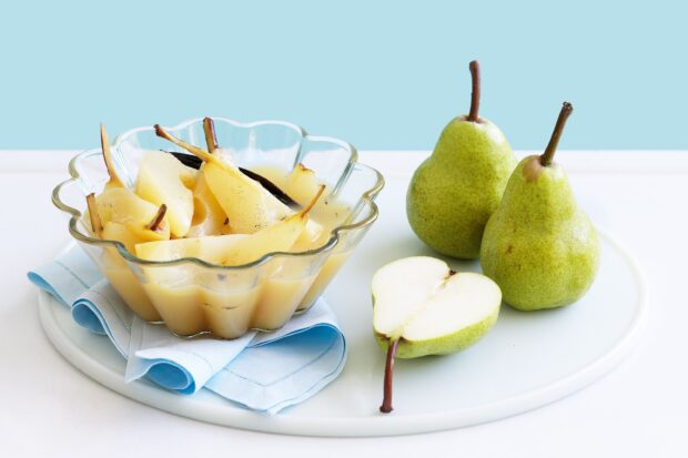 A bowl of cooked pear slices and fresh pear fruits on a white plate with a blue napkin