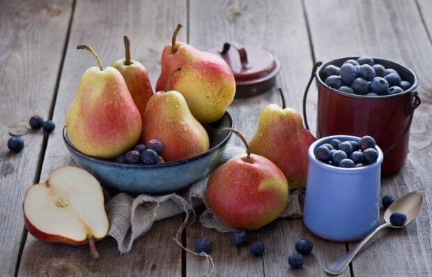 Fresh ripe pears with blueberries arranged on a rustic wooden table