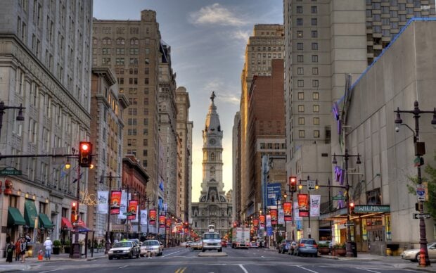 The historic city hall tower in Pennsylvania stands tall between busy downtown streets
