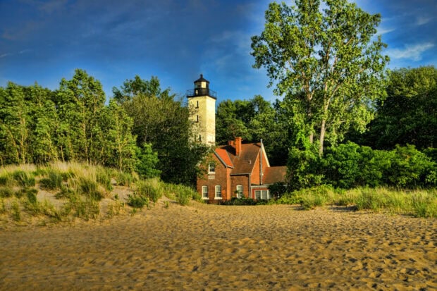 Historic lighthouse surrounded by trees and sandy dunes in Pennsylvania