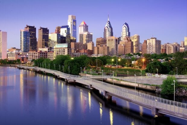 A scenic view of the Pennsylvania cityscape with riverside walkway and modern buildings at dusk