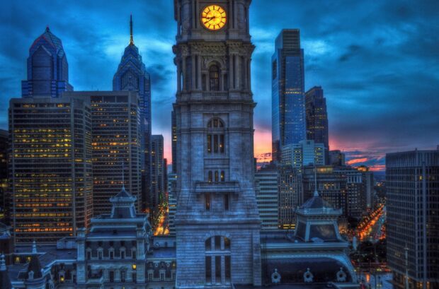The cityscape of Pennsylvania with a historic clock tower and modern skyscrapers at sunset