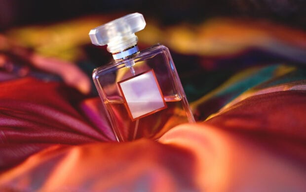 A perfume bottle placed on colorful fabric with warm lighting and perfume as the main subject