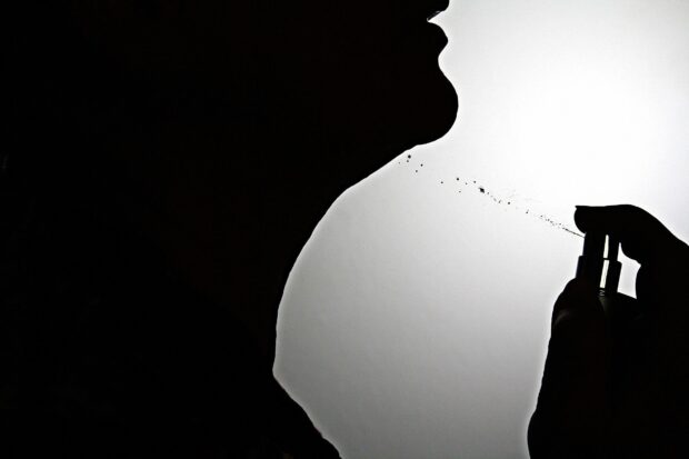 A close up of perfume being sprayed on neck silhouette