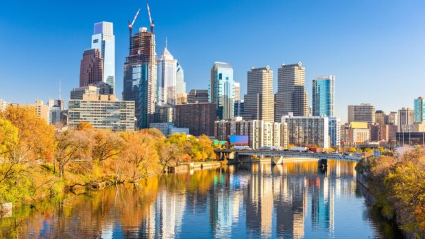 Philadelphia city skyline with autumn trees reflecting in the river during a clear sunny day