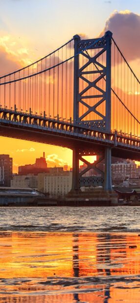 The sunset view of Philadelphia Pennsylvania bridge with city skyline and water reflection