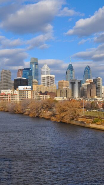 Philadelphia Pennsylvania skyline with buildings near a river under a blue sky with clouds