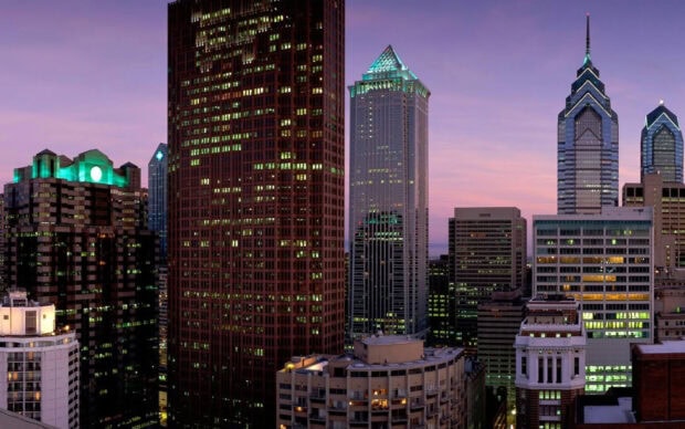 Philadelphia city skyline with tall buildings lit up at dusk in Pennsylvania