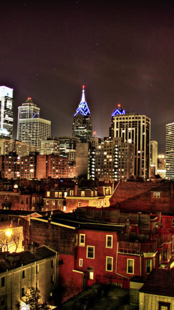 Nighttime cityscape of Philadelphia Pennsylvania skyline with illuminated buildings and residential houses