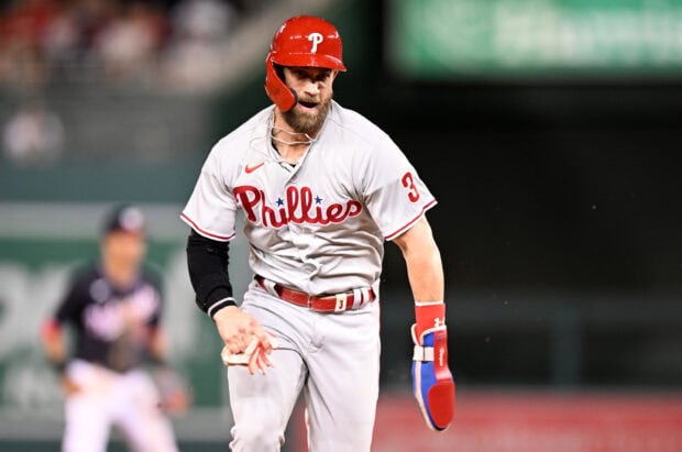 A Philadelphia Phillies player wearing a red helmet and gray uniform running on the baseball field