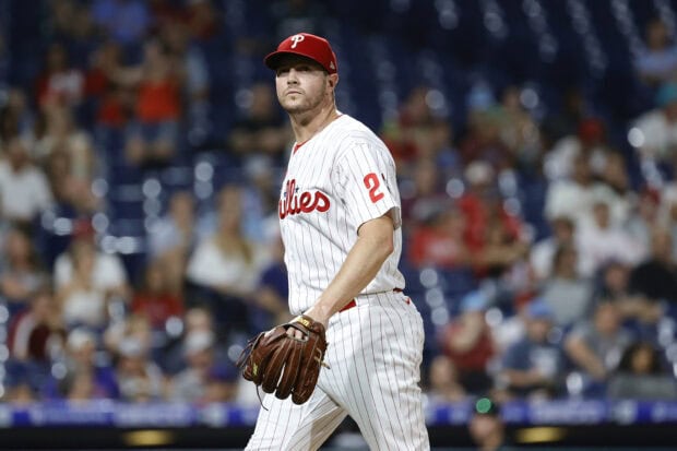 A Philadelphia Phillies player wearing a white pinstriped jersey walking on the field