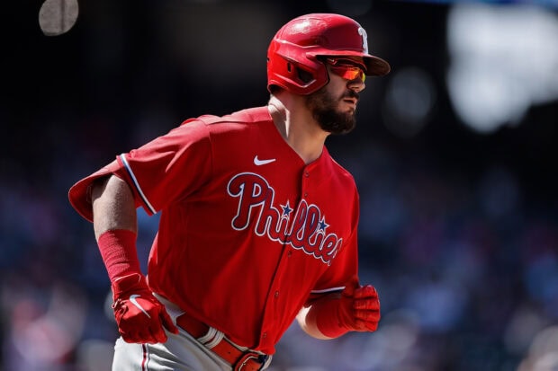 A Philadelphia Phillies player running on the field wearing a red uniform and helmet