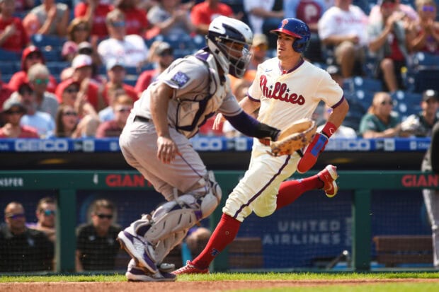 A Philadelphia Phillies player running towards the base during a baseball game with a catcher nearby