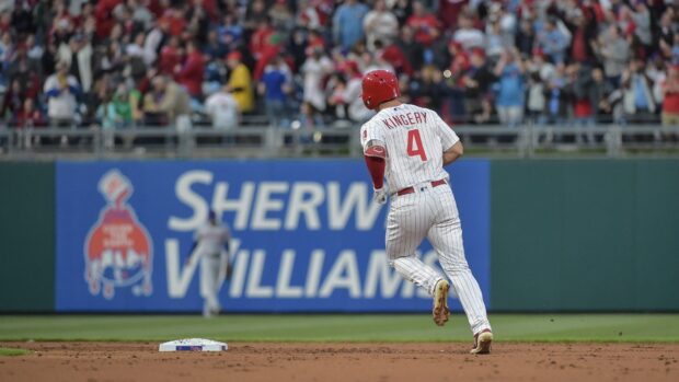 A baseball player from the Philadelphia Phillies running to a base during a game in a crowded stadium