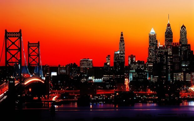 Philly skyline at sunset with illuminated buildings and a bridge over the river