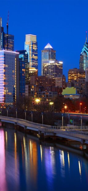 Evening view of the Philly skyline reflecting on the river with illuminated buildings