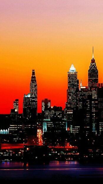 Philly skyline visible at dusk with glowing buildings and vibrant orange sky