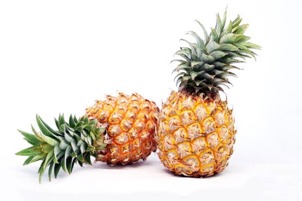 Two fresh pineapple with green leaves on a white surface background