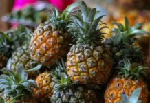 A close up view of ripe pineapple fruits with green leaves in a market setting