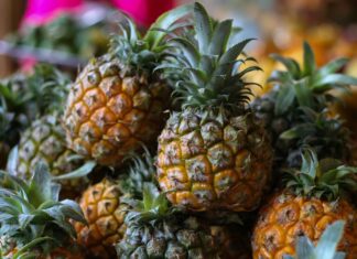 A close up view of ripe pineapple fruits with green leaves in a market setting