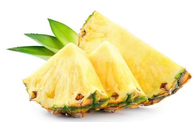 Fresh pineapple slices with green leaves on a white background