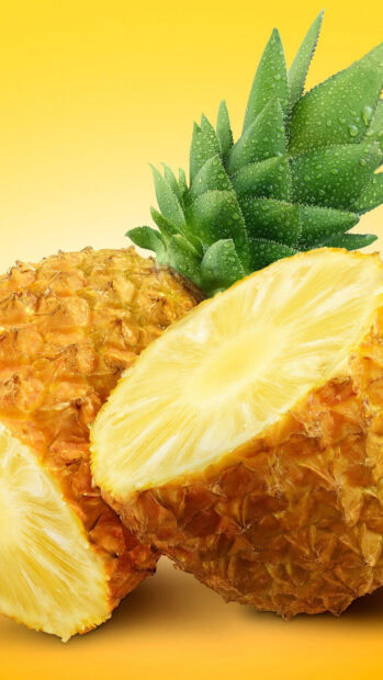 Fresh pineapple with green leaves and juicy slices on yellow background