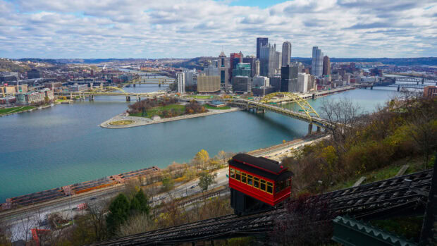A scenic view of Pittsburgh cityscape featuring a red incline car ascending the hillside
